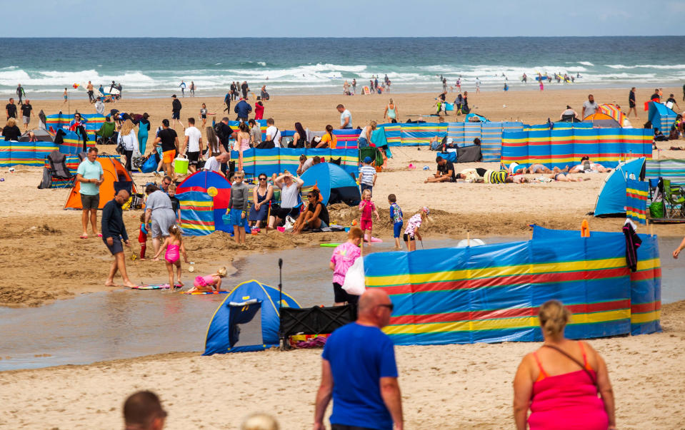 Tourists flocks to the Perranporth beach in Cornwall. 1st August 2020. See SWNS story SWPLtourism; Cornwall residents fear a local lockdown and say they are "scared to leave their houses"  - as some of the county's beaches are likened to "Benidorm on steroids". Some of the more popular seaside destinations along the south-west coast have seen trails of cars queuing through the town as visitors flock to beaches or holiday parks in search of a 'staycation'. But locals in these popular towns have been left feeling "uneasy" about leaving their homes - and some fear they could be in for a local lockdown set to be worse than the first lockdown. Tina-Marie Lally, from Penzance, tried to visit Porthminster Beach in St Ives last week - but shared photos on Facebook of the beach crowded with people and windbreakers.