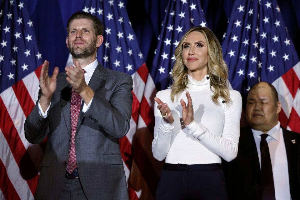 Eric Trump and Lara Trump applaud in front of American flags