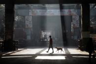 A man and a stray dog cross a road during a 21-day nationwide lockdown to limit the spreading of coronavirus disease (COVID-19), in Kolkata