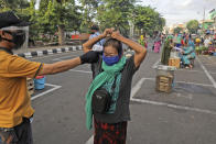 A city official takes the temperature reading of a vendor as others sit on a marked positions to maintain physical distancing in an attempt to curb the spread of the new coronavirus outbreak at a traditional market in Surabaya, East Java, Indonesia, Wednesday, June 3, 2020. (AP Photo/Trisnadi)