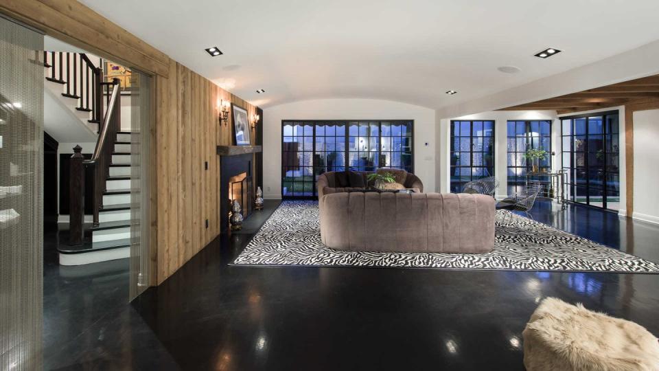 <p>The home's interiors reveal the many additions and renovations it's seen throughout its history, though; here, a spacious open floor plan with modern, black floors pairs with wood paneling and French doors. </p>