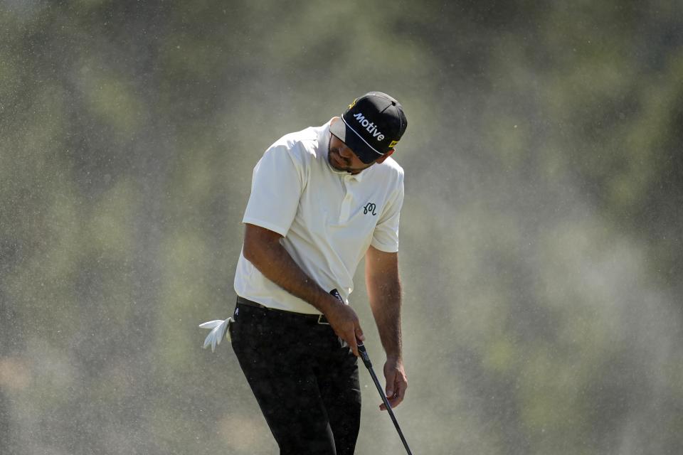 Jason Day, of Australia, shields himself from blowing sand on the 18th hole during second round at the Masters golf tournament at Augusta National Golf Club Friday, April 12, 2024, in Augusta, Ga. (AP Photo/Ashley Landis)