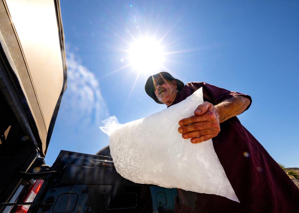 Nick Van Nice loads a bag of ice into his vehicle in Phoenix on July 19, 2023, on the 20th day in a row of temperatures of 110 degrees or more, which set a new record.