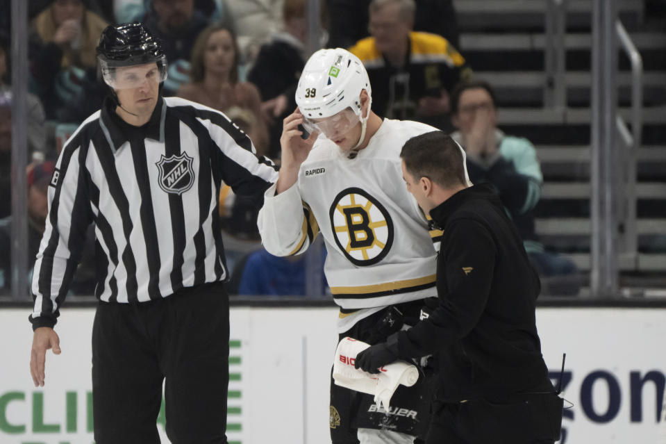 Boston Bruins forward Morgan Geekie, center, is helped from the ice during the second period of an NHL hockey game against the Seattle Kraken, Monday, Feb. 26, 2024, in Seattle. (AP Photo/Stephen Brashear)