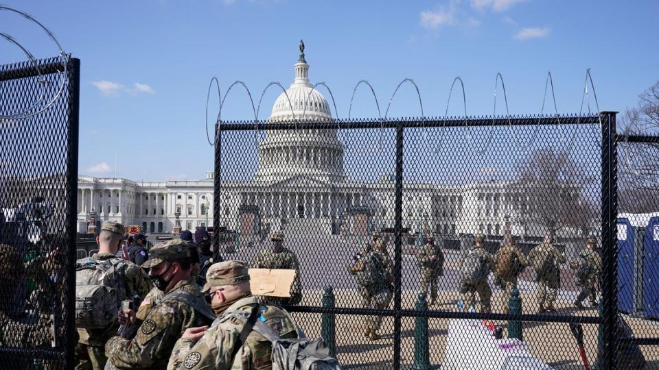 Soldaten der Nationalgarde gehen durch das Tor eines Sicherheitszauns vor dem Kapitol.