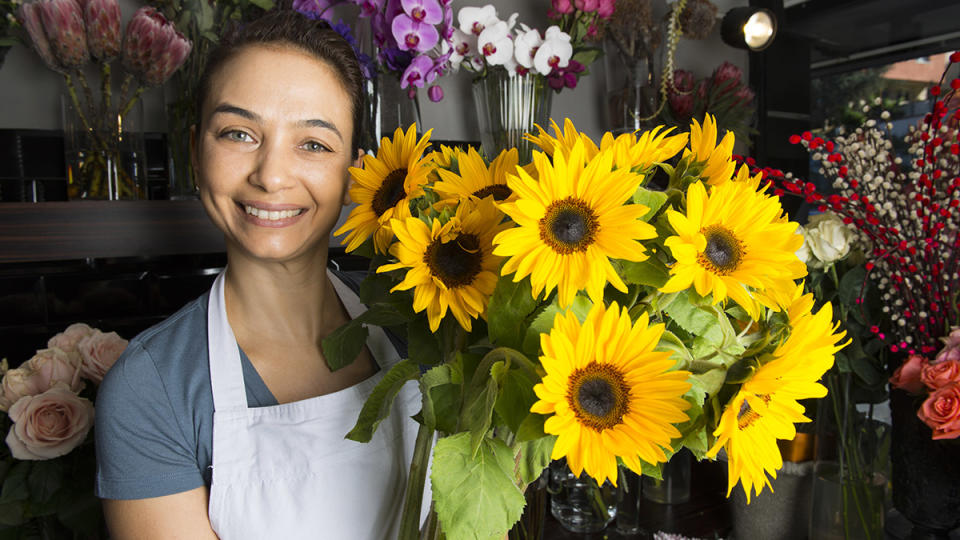 Woman with beautiful skin next to sunflowers, the oil of which helps skin glow