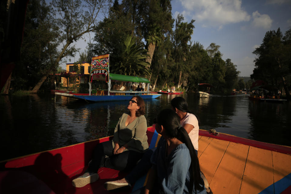 Colombian tourist Teresita Cortes Castillo, center, and her two daughters, take a ride on a trajinera, the colorful boats typically rented by tourists, families, and groups of young people, in Xochimilco, Mexico City, Friday, Sept. 6, 2019. The usually festive Nativitas pier was subdued and largely empty Friday afternoon, with some boat operators and vendors estimating that business was down by 80% on the first weekend following the drowning death of a youth that was captured on cellphone video and seen widely in Mexico. Borough officials stood on the pier to inform visitors of new regulations that went into effect Friday limiting the consumption of alcohol, prohibiting the use of speakers and instructing visitors to remain seated.(AP Photo/Rebecca Blackwell)