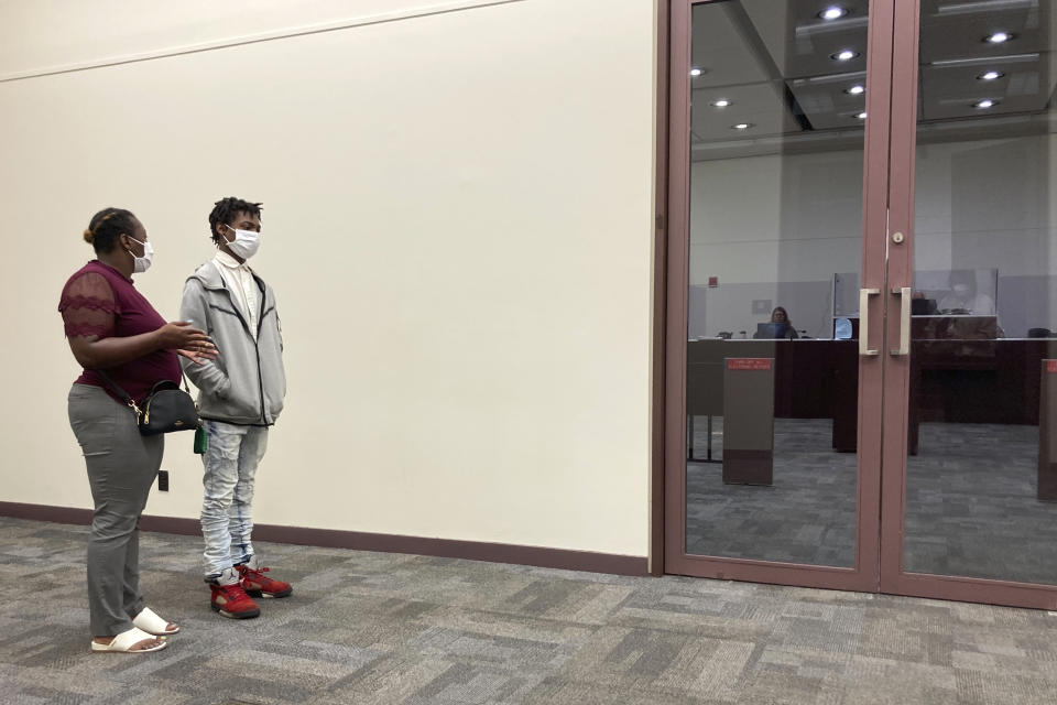 Keyon Robinson, 19, and his mother, Nicole Bryant, wait outside a courtroom after a status hearing for Robinson's gun case on Wednesday, Aug. 10, 2022, at the Circuit Court of Cook County in Maywood, Ill. Robinson was arrested with a gun in his backpack outside his high school in Oak Park, Ill., and is facing felony charges. Robinson said he took the gun to school to protect himself after an altercation with a relative and had no intentions of hurting anyone. (AP Photo/Martha Irvine)