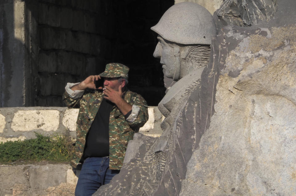 A man speaks phone near a monument in Berdzor, the separatist region of Nagorno-Karabakh, Sunday, Nov. 1, 2020. Fighting over the separatist territory of Nagorno-Karabakh entered sixth week on Sunday, with Armenian and Azerbaijani forces blaming each other for new attacks. (AP Photo)