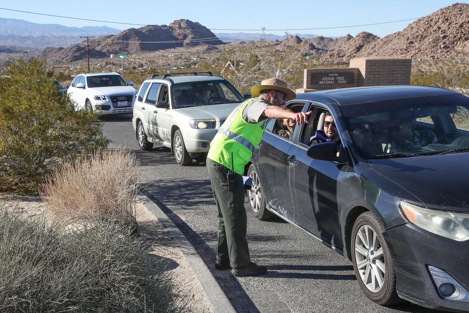 Superintendent David Smith helps direct incoming traffic into Joshua Tree National Park's west entrance Jan. 24, 2022. “Go ahead and enter,” he shouts, quickly waving dozens of cars past the West Visitors’ entrance kiosk to break up a thick knot of idling vehicles.