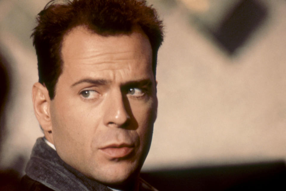 Bruce Willis in a scene, looking to the side with a concerned expression, wearing a jacket