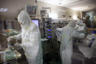 In this photo taken on Friday, March 27, 2020, healthcare workers assist a patience at one of the intensive care units (ICU) at German Trias i Pujol hospital in Badalona, in the Barcelona province, Spain. The new coronavirus causes mild or moderate symptoms for most people, but for some, especially older adults and people with existing health problems, it can cause more severe illness or death. (AP Photo/Anna Surinyach)