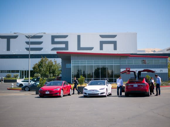 Tesla vehicles and people outside Tesla's factory.