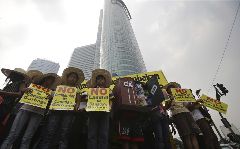 FILE - In this May 7, 2015, file photo, Filipino environmental activists hold slogans about the 50 containers of waste that were shipped from Canada to the Philippines two years ago, during a protest outside the Canadian embassy at the financial district of Makati, south of Manila, Philippines. The Philippine foreign secretary said Thursday, May 16, 2019, the ambassador and consuls in Canada are being recalled over Ottawa's failure to take back truckloads of garbage that Filipino officials say were illegally shipped to the Philippines years ago. (AP Photo/Aaron Favila, File)