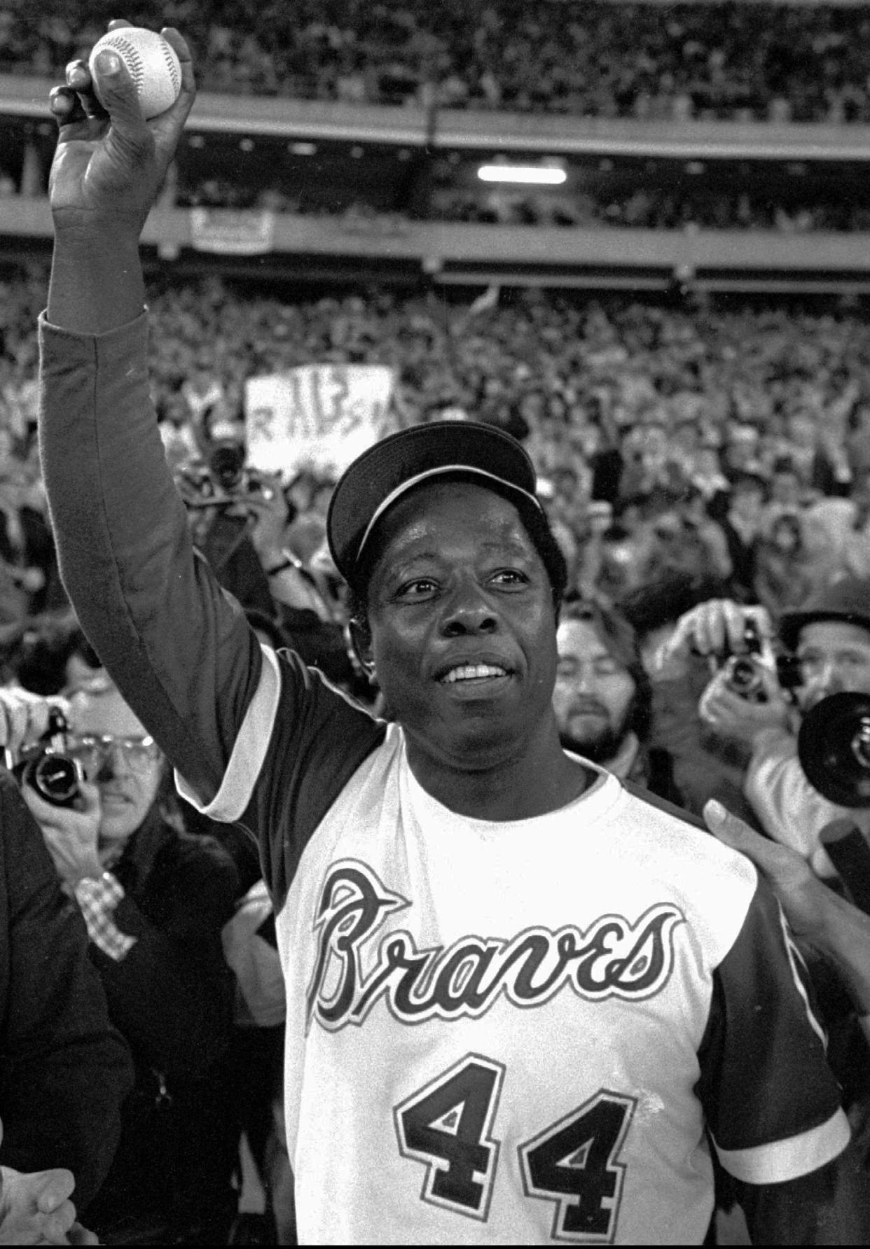 FILE - Atlanta Braves' Hank Aaron holds aloft the ball he hit for his 715th career home in Atlanta. Aaron, who endured racist threats with stoic dignity during his pursuit of Babe Ruth but went on to break the career home run record in the pre-steroids era, died early Jan. 22, 2021. He was 86. (AP Photo, File)