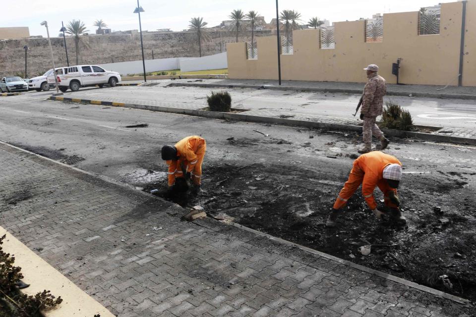 Cleaners work at the scene of a car bomb explosion outside the Corinthia hotel in Libya's capital Tripoli