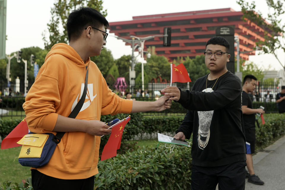 A man hands out national flags to others arriving for the NBA preseason game to be held at the Mercedes Benz Arena in Shanghai, China, Thursday, Oct. 10, 2019. All media events such as news conferences have been canceled inside the arena hosting Thursday's NBA preseason game in China between the Los Angeles Lakers and Brooklyn Nets, though the matchup itself remains on as scheduled. (AP Photo)