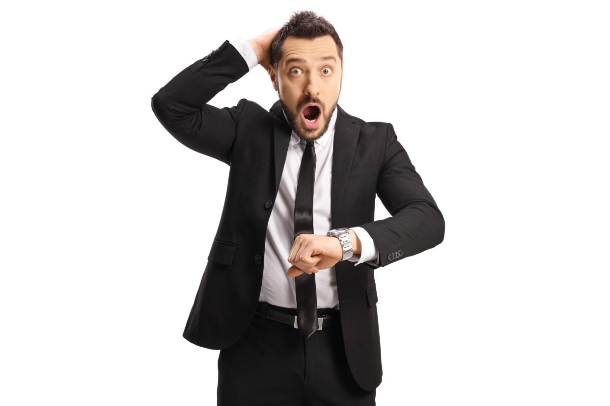 Shocked businessman checking his wristwatch and holding his head isolated on white background