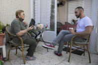 Israeli Itamar Glazer, right, sits with 85-year-old Holocaust survivor Sara Weinsten during a visit in Yavne, Israel, Thursday, Oct. 8, 2020. For thousands of older Israelis like Weinsten, being housebound alone during Israel's second nationwide lockdown due to the coronavirus pandemic is difficult and depressing. But each week ahead of the Jewish Sabbath, which starts on Friday at sundown, a home-baked cake is delivered by one of thousands of volunteers bringing pastries to home-bound older Israelis. (AP Photo/Sebastian Scheiner)