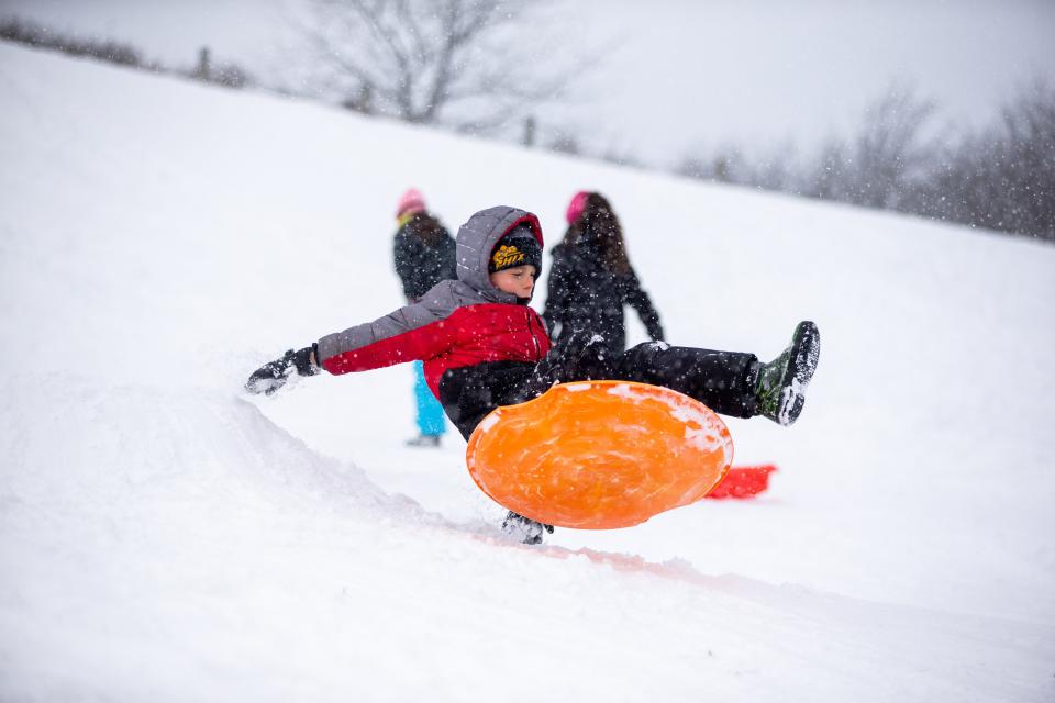 Kids fly off a snowy ramp while sledding Thursday, Jan. 6, 2022, at Van Raalte Farm Park.