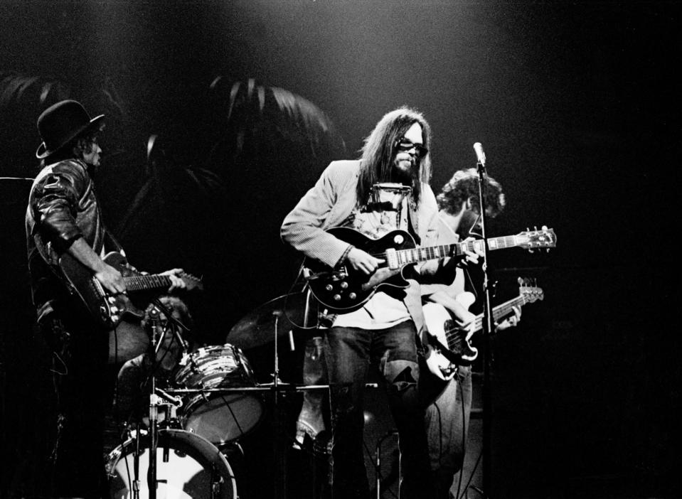 Neil Young performs on stage with The Santa Monica Flyers on the 'Tonight's The Night' tour at the Rainbow Theatre, London, 5th November 1973, L-R Nils Lofgren, Ralph Molina, Neil Young, Billy Talbot. (Photo by Gijsbert Hanekroot/Redferns)