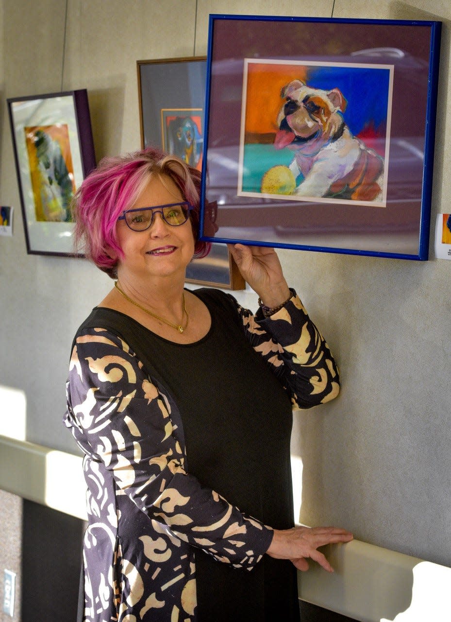 The work of artist Rebecca Booth is currently on display at The Healing Wall at Magruder Hospital. She is shown here with the painting of a bulldog that she created for a Toledo Humane Society Fundraiser.