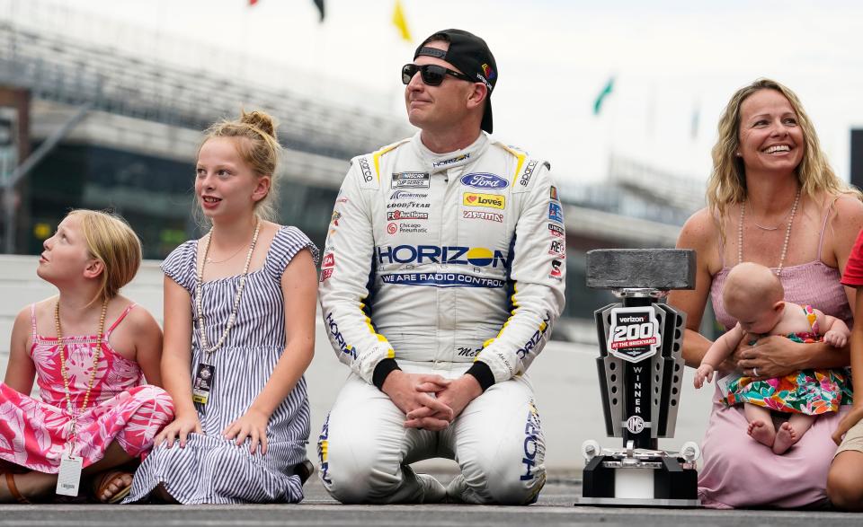 Michael McDowell kneels down with his family to kiss the bricks at Indianapolis Motor Speedway after winning the Verizon 200 at the Brickyard on Sunday.