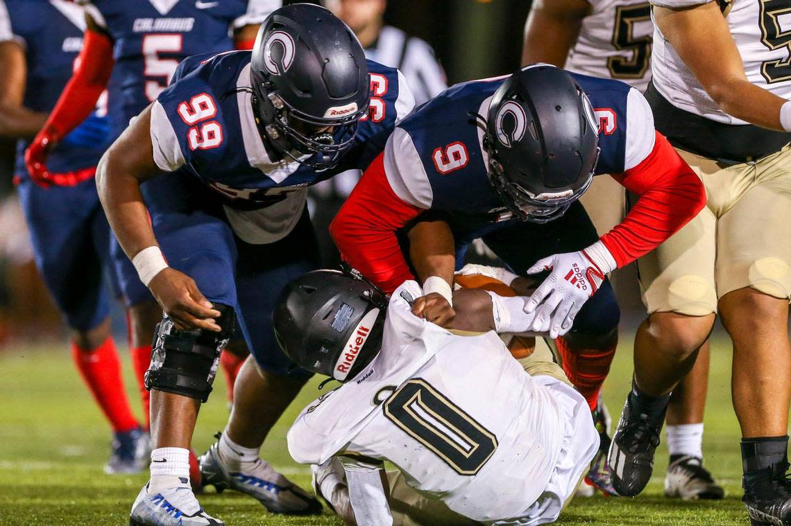 Columbus defensive tackle Derrick Hart (99) and defensive tackle Daylen Russell (9) tackle Ocoee running back Keyondray Jones (0) during the second quarter of a high school football semifinal game at Tropical Park in Miami, Florida, Friday, December 2, 2022.