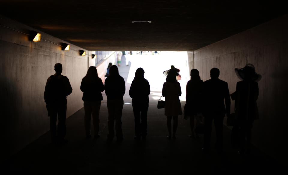 Fans pause as the national anthem is played before the 140th running of the Kentucky Derby horse race at Churchill Downs Saturday, May 3, 2014, in Louisville, Ky. (AP Photo/David Goldman)