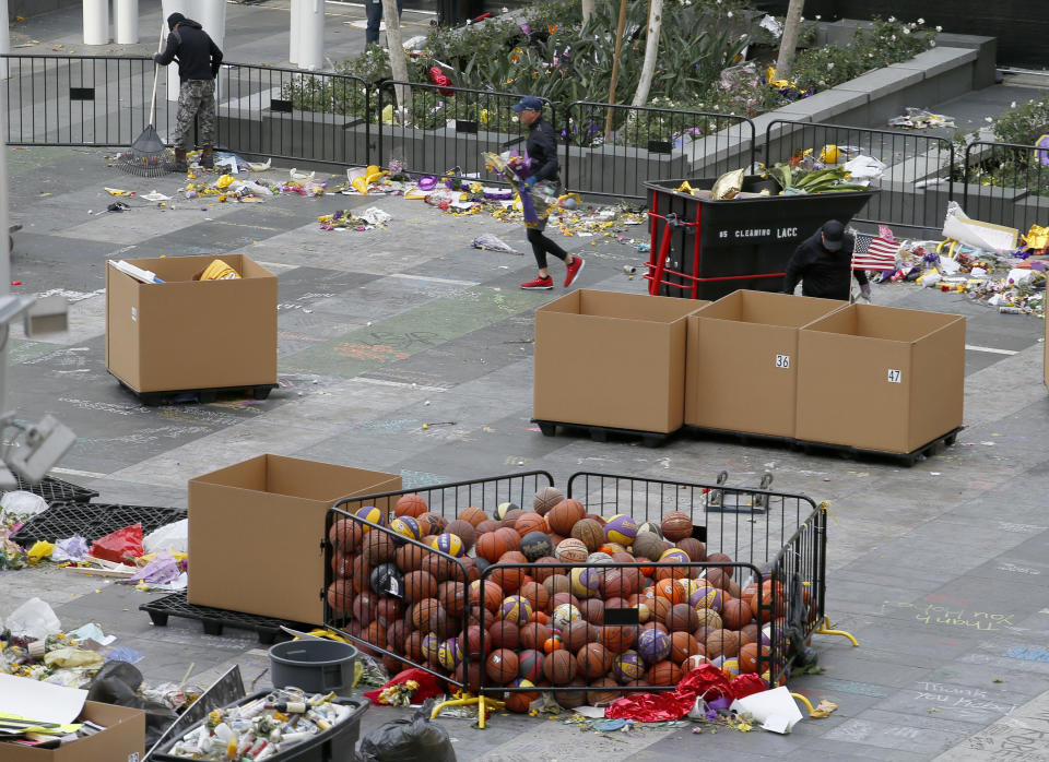 Workers remove thousands of items left in honor of Kobe Bryant, including hundreds of basketballs, from X-Box Plaza across Chick Hearn Court from Staples Center, home of the Los Angeles Lakers, early Monday, Feb. 3, 2020, in Los Angeles. Mourners left the items after the death of the former Lakers legend, his daughter and seven others, in a helicopter crash one week ago. (AP Photo/Reed Saxon)