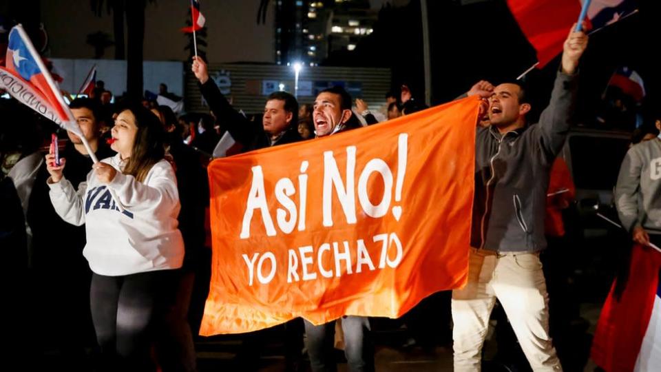 Un grupo de personas agitan una pancarta contra el proeyecto constitucional chileno.