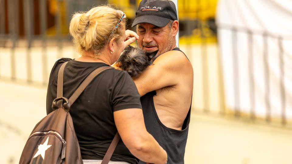 Two people evacuated by the fire hug their dog on Saturday in La Orotava. - Europa Press News/Getty Images