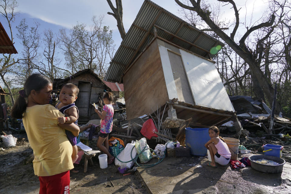 Residents stand amid damaged homes following Typhoon Rai in Talisay, Cebu province, central Philippines on Saturday, Dec. 18, 2021. The strong typhoon engulfed villages in floods that trapped residents on roofs, toppled trees and knocked out power in southern and central island provinces, where more than 300,000 villagers had fled to safety before the onslaught, officials said. (AP Photo/Jay Labra)