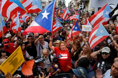 Demonstrators chant, wave Puerto Rican flags, and drink champagne celebrating the official resignation of now ex-governor of Puerto Rico Ricardo Rossello, in San Juan