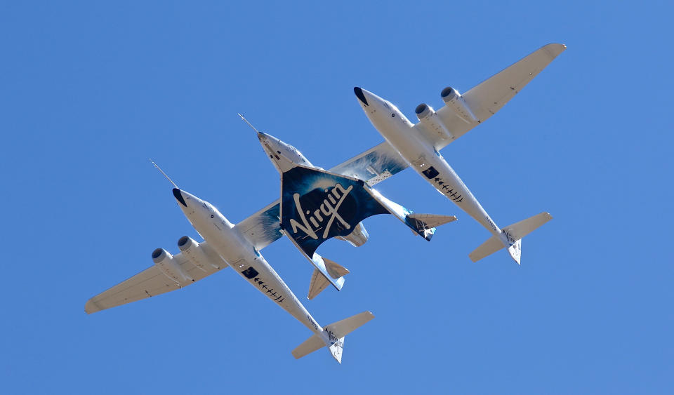 Virgin Galactic's VSS Unity departs Mojave Air & Space Port in Mojave, Calif. for the final time as Virgin Galactic shifts its SpaceFlight operations to New Mexico on Thursday, Feb. 13, 2020. Virgin Galactic's spaceship VSS Unity, tucked under the wing of its special carrier aircraft, headed east from Southern California on a long-awaited ferry flight to its new home in New Mexico where it will be prepared for commercial operations carrying tourists on hops into space, the company said. (Matt Hartman via AP)