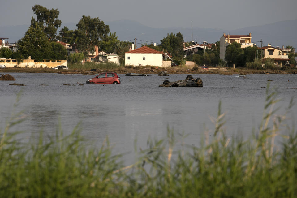 Sunken vehicles following a storm at the village of Bourtzi, on Evia island, northeast of Athens, on Sunday, Aug. 9, 2020. Five people, including en elderly couple and an 8-month-old baby have been found dead, two more are missing and dozens have been trapped in their homes and cars as a storm hits the island of Evia in central Greece, authorities said Sunday. (AP Photo/Yorgos Karahalis)