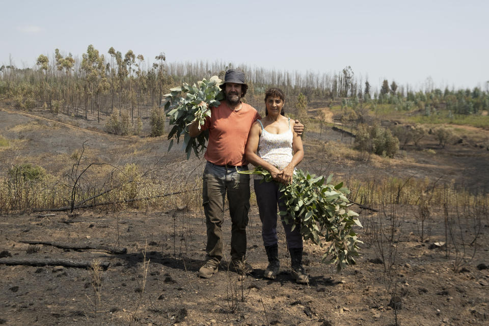 Fernando Gonçalves, left, and Sueli, right, pose for a photo at their property burnt during a fire at the village of Roda, near Macao, in central Portugal on Tuesday, July 23, 2019. Emergency services in Portugal have brought under control a huge wildfire which raged for four days and injured 39 people. Civil Protection Agency commander Luis Belo Costa says around 1,000 firefighters are watching out for smoldering hotspots amid temperatures close to 40 degrees Celsius and gusting winds. (AP Photo/Sergio Azenha)