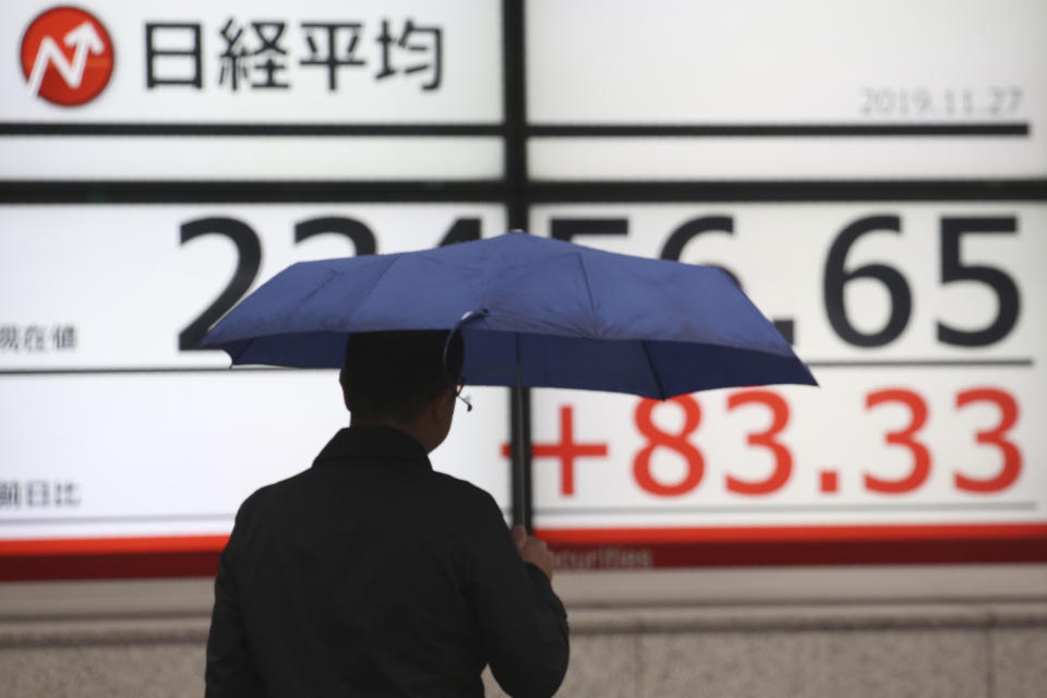 A man walks by an electronic stock board of a securities firm in Tokyo, Wednesday, Nov. 27, 2019. Shares were mostly higher in Asia on Wednesday after a fresh set of record highs on Wall Street, spurred by encouraging signs on trade talks between the U.S. and China. (AP Photo/Koji Sasahara)