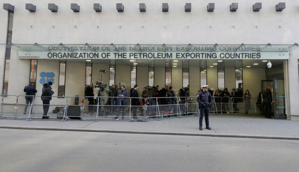 People stand in front of the headquarters of the Organization of the Petroleum Exporting Countries, OPEC, in Vienna, Austria, Thursday, March 5, 2020. (AP Photo/Ronald Zak)