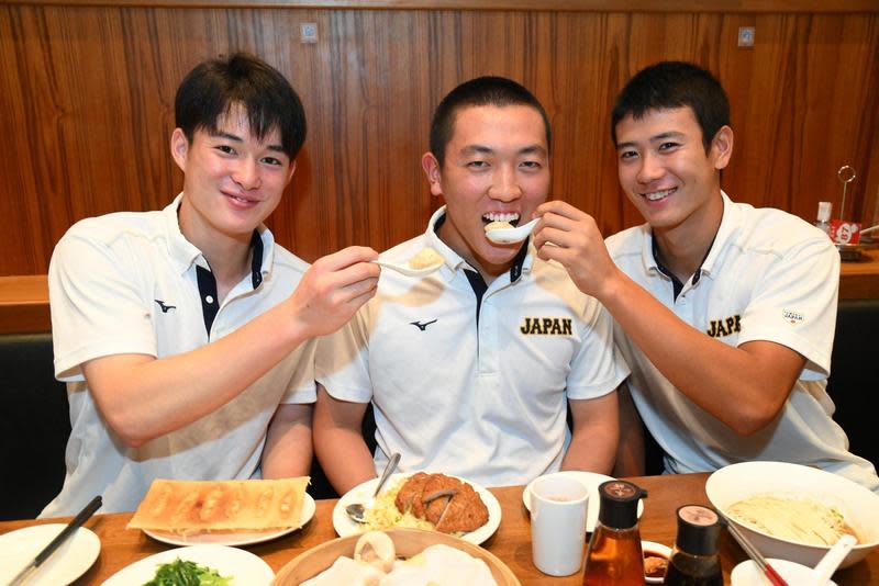 日本U18成員開心吃小籠包，丸田湊斗（左）、山田脩也（右）餵食剛出院的隊長小林隼翔（中）。（翻攝自@hsbaseball_yomi推特）