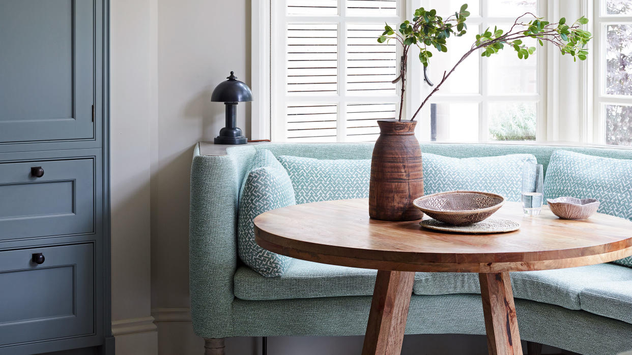  blue couch, wooden table and cabinetry by window 