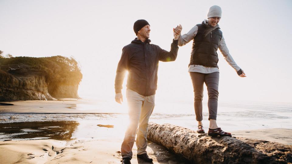 A senior couple explores a beach in Oregon state, enjoying the beauty of sunset on the Pacific Northwest coast.