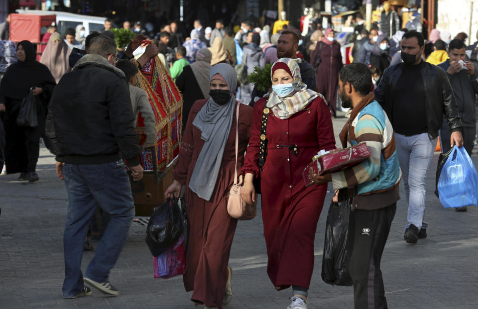 People, some wearing masks to help prevent the spread of the coronavirus, shop for the Muslim holy month of Ramadan, at the main market in Gaza City, Sunday, April 11, 2021. More than a year into the coronavirus pandemic, the worst fears are now coming true in the crowded, blockaded Gaza Strip: A sudden surge in infections and deaths is threatening to overwhelm hospitals weakened by years of conflict and Israeli border closures. (AP Photo/Adel Hana)