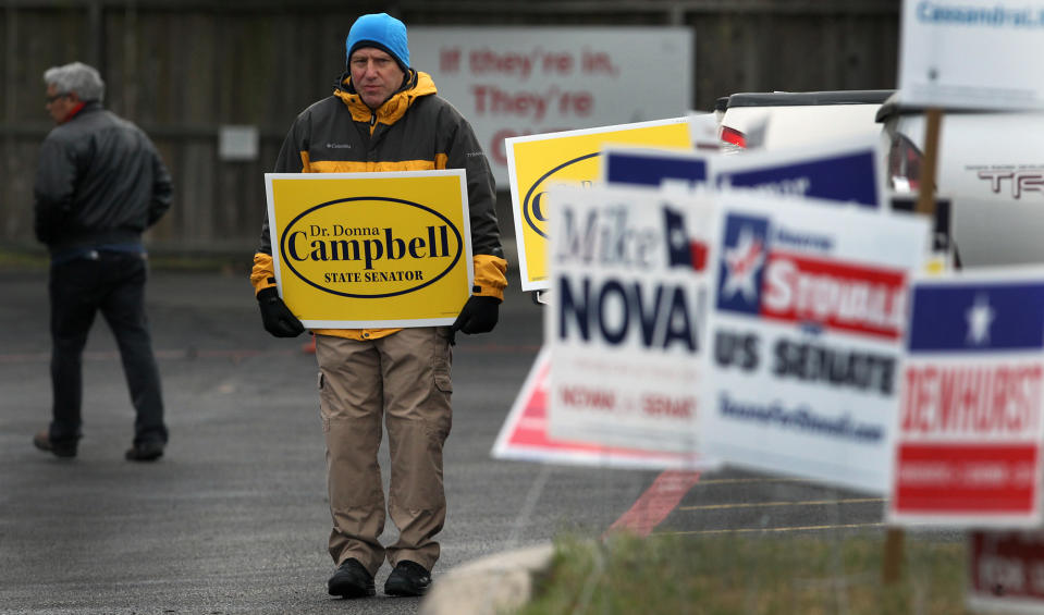 Marcus Booth, center, holds a sign at the Brook Hollow Branch of the San Antonio Public Library on election day, Tuesday, March 4, 2014, in San Antonio, Texas. Texas is holding the nation's first primary election Tuesday with a political free-for-all in Republican races that could push the state further right, though Democrats are calling it the next big battleground on the electoral map. (AP Photo/The San Antonio Express-News, John Davenport) RUMBO DE SAN ANTONIO OUT; NO SALES