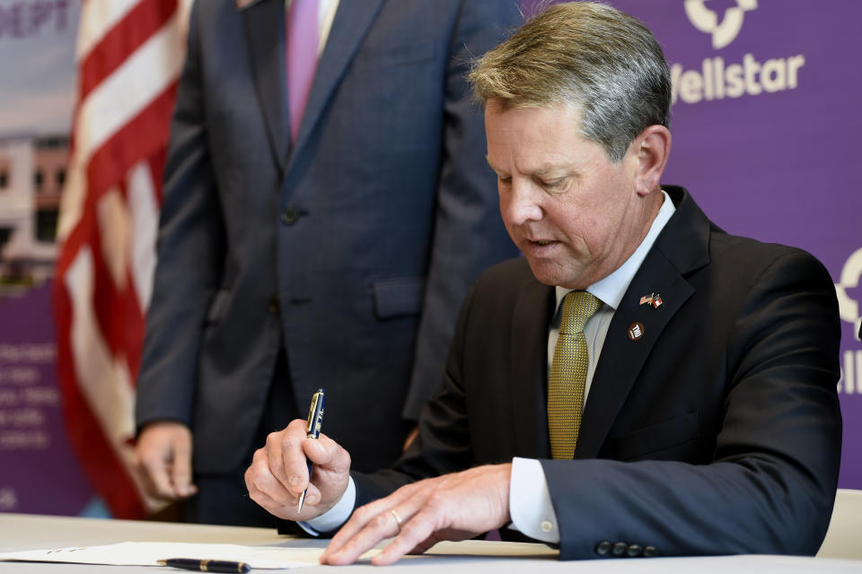 Georgia Gov. Brian Kemp signs House Bill 521 at Wellstar Kennestone Hospital, Thursday, July 16, 2020, in Marietta, Ga. Mayors in Atlanta and other Georgia cities deepened their defiance of Gov. Kemp on Thursday, saying they want their requirements for people to wear masks in public to remain in place, even after the Republican governor explicitly forbade cities and counties from mandating face coverings.(AP Photo/Mike Stewart)