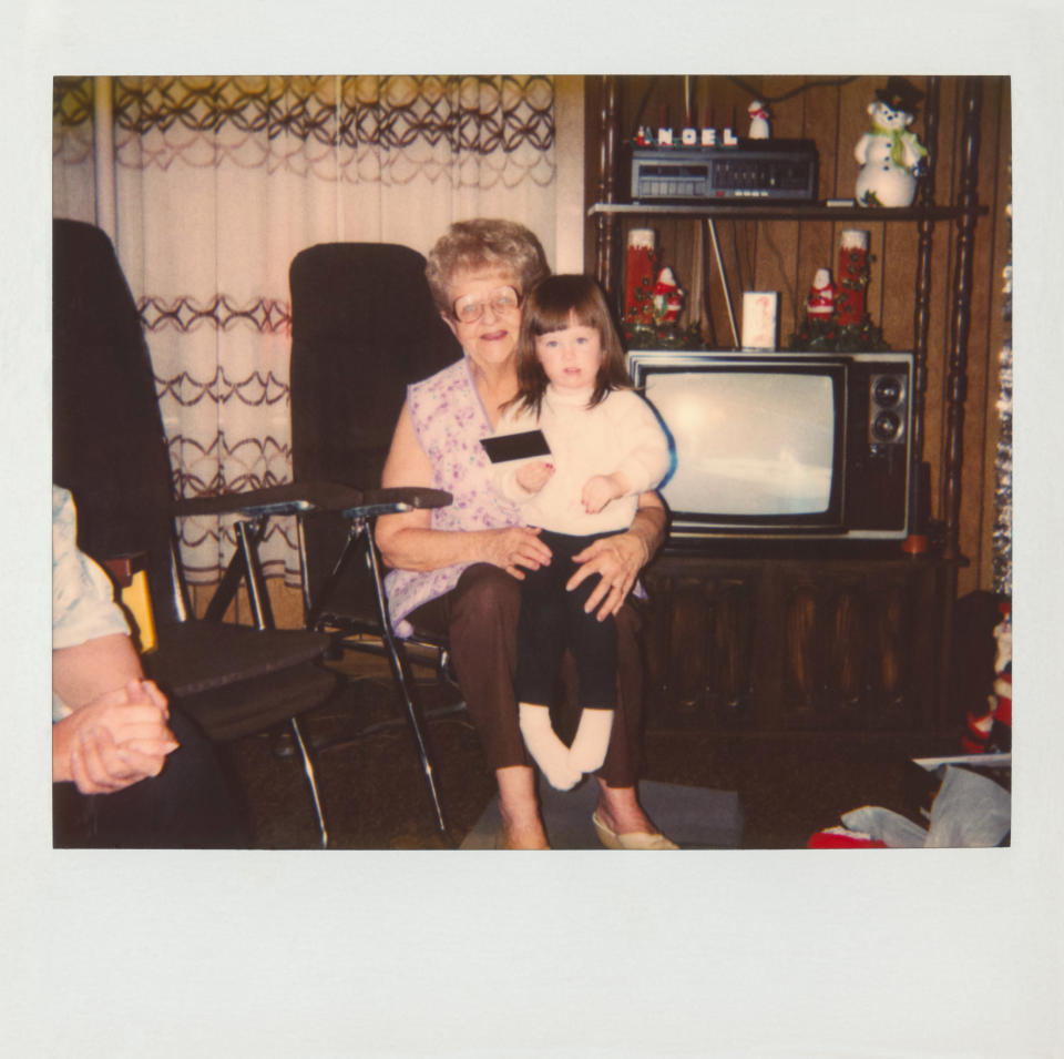 A Polaroid photo of a grandma and her grandchild sitting in front of a TV