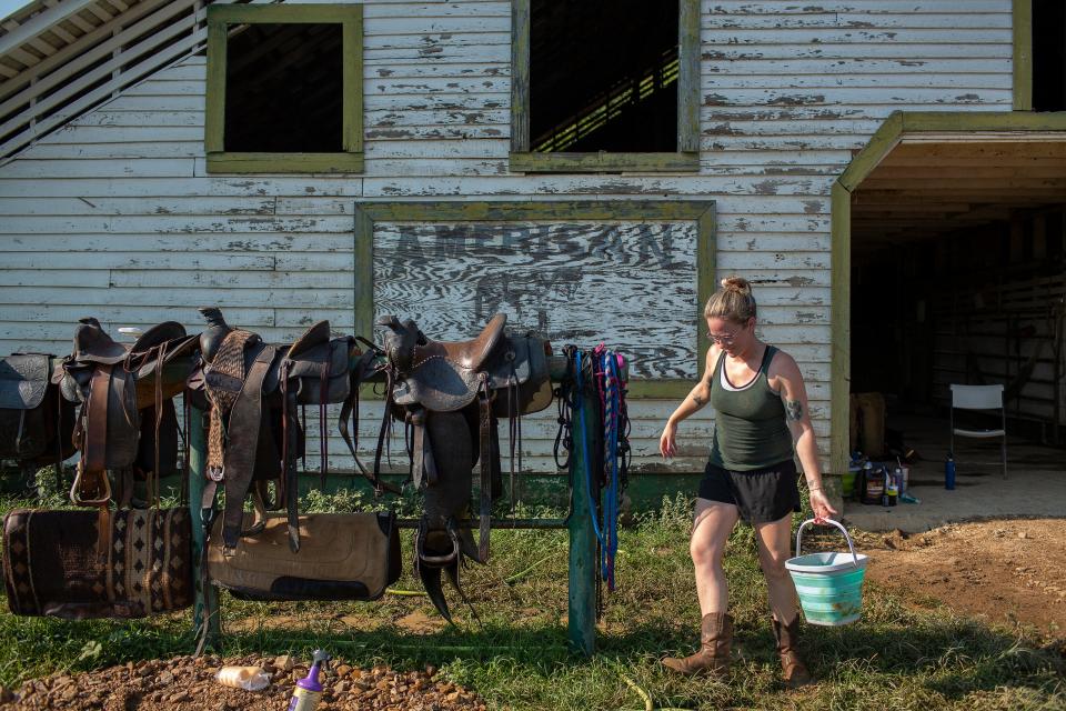 Anna McCormick Rowe prepares to clean saddles exposed to flood waters at the  McCormick family's ranch near Nunnelly, Tenn., on Tuesday, Aug. 24, 2021.