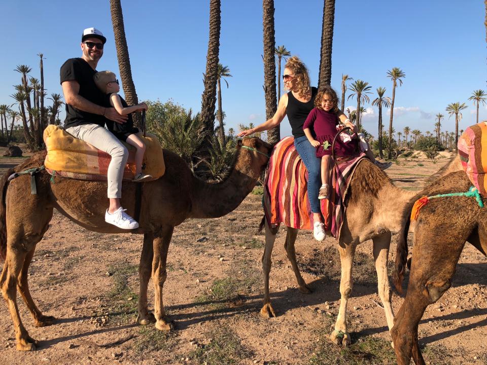 A family riding camels, with a father and son on one and mother and daughter on the other.