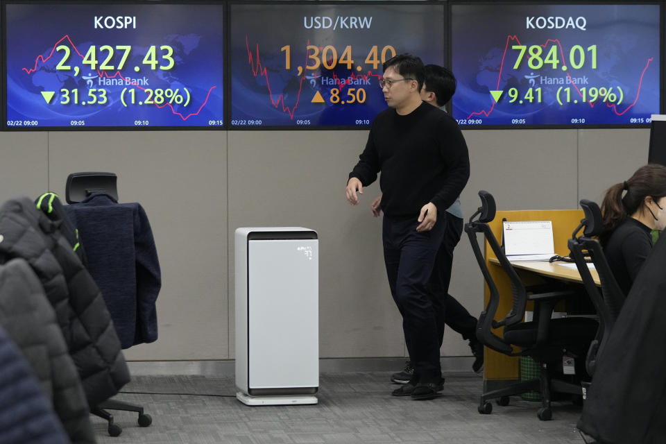 Currency traders pass by the screens showing the Korea Composite Stock Price Index (KOSPI), left, and the foreign exchange rate between U.S. dollar and South Korean won, center, at the foreign exchange dealing room of the KEB Hana Bank headquarters in Seoul, South Korea, Wednesday, Feb. 22, 2023. Asian shares declined Wednesday after stocks tumbled on Wall Street as worries persist about higher interest rates and their tightening squeeze on the global economy. (AP Photo/Ahn Young-joon)