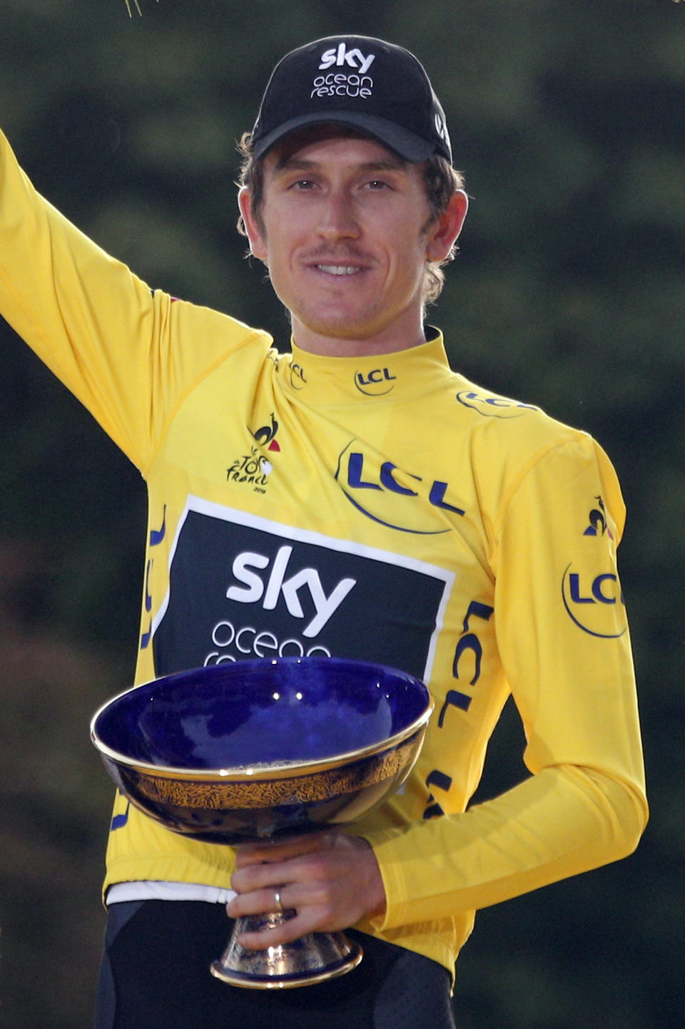 FILE - In this Sunday July 29, 2018 file picture, tour de France winner Britain's Geraint Thomas, wearing the overall leader's yellow jersey, celebrates on the podium on the Champs-Elysees avenue in Paris, France. The team said in a statement on Wednesday that police is investigating the case after the trophy disappeared during an event organized in Birmingham, where Team Sky displayed the three Grands Tours trophies won by its riders. (AP Photo/Francois Mori, File)